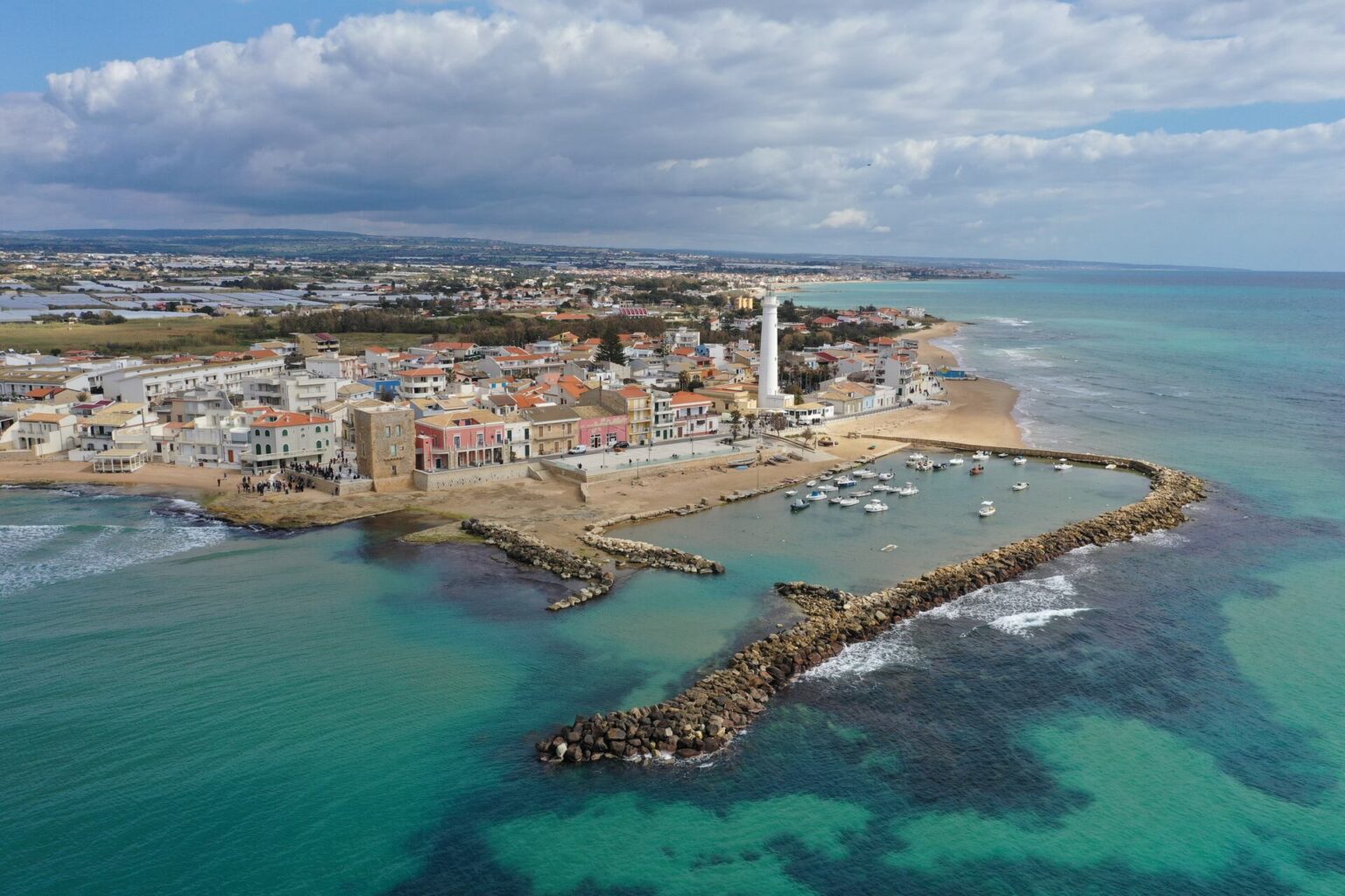 Veduta aerea di Punta Secca, il borgo di Montalbano: il faro, la spiaggia e il porticciolo turistico vicino a Ragusa.