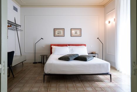 Interno camera Luigi presso Castellett Ragusa: letto matrimoniale moderno su pavimento d'epoca siciliano con dettagli architettonici conservati.