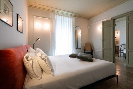 Interno della stanza Luigi presso Castellett Ragusa: letto matrimoniale moderno, dettagli architettonici classici e illuminazione soffusa.